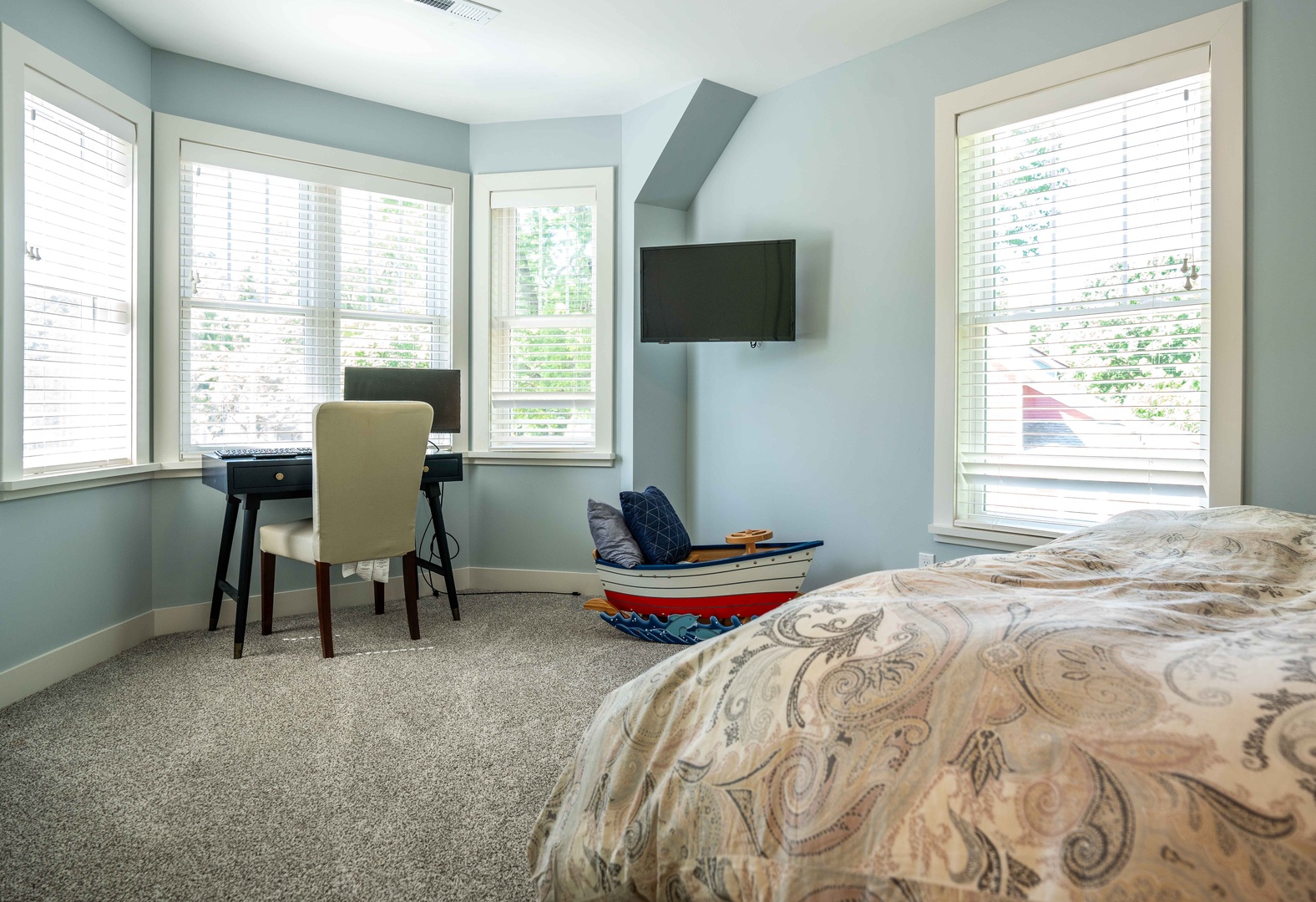 The second bedroom sanctuary features a plush queen bed, smart TV, and laptop workspace