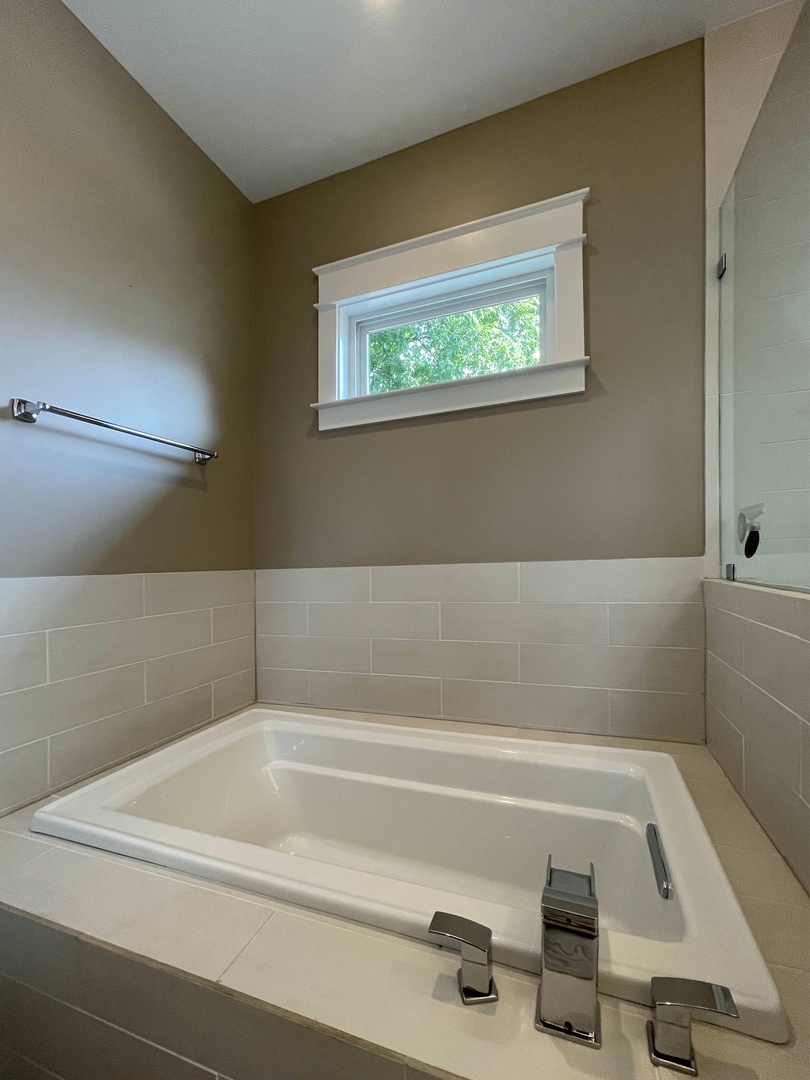 En suite bathroom with soaking tub, dual sinks, and standing shower