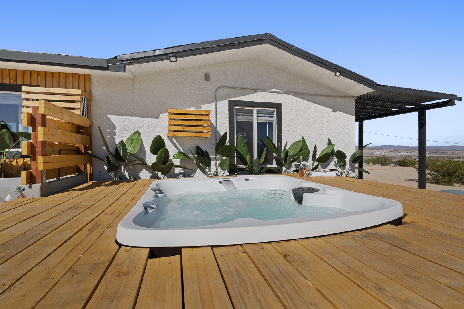 2nd side yard with sun bathing mats, large hot tub deck, outdoor tub, and shower