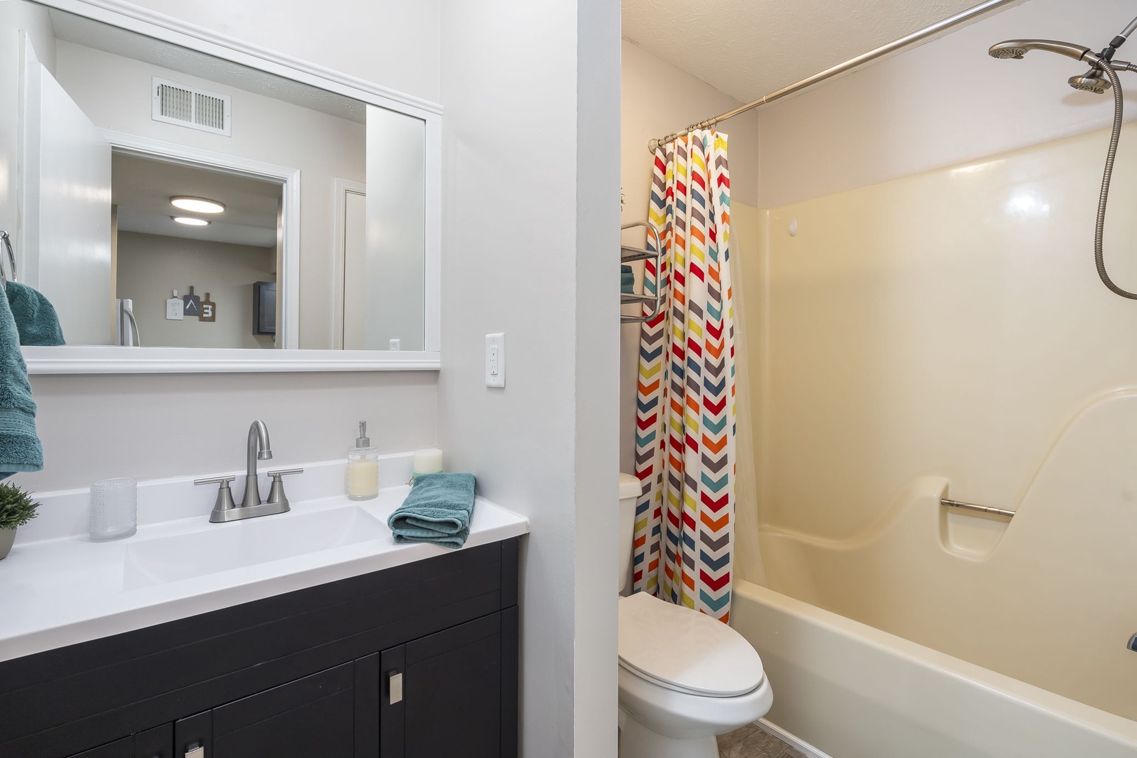 The chic bathroom contains a single vanity & shower/tub combo