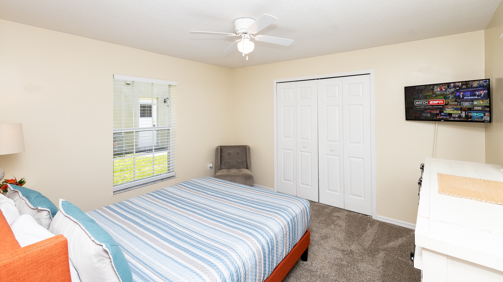 This cozy queen bedroom includes a smart TV and ceiling fan