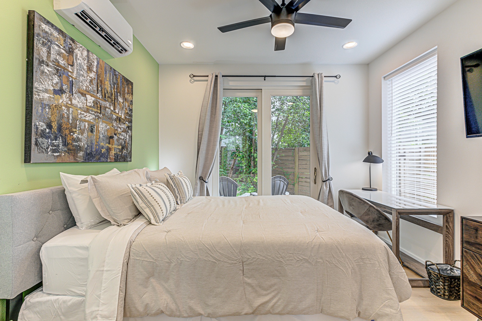 Bedroom 1 with queen bed, patio, workspace, and Smart TV