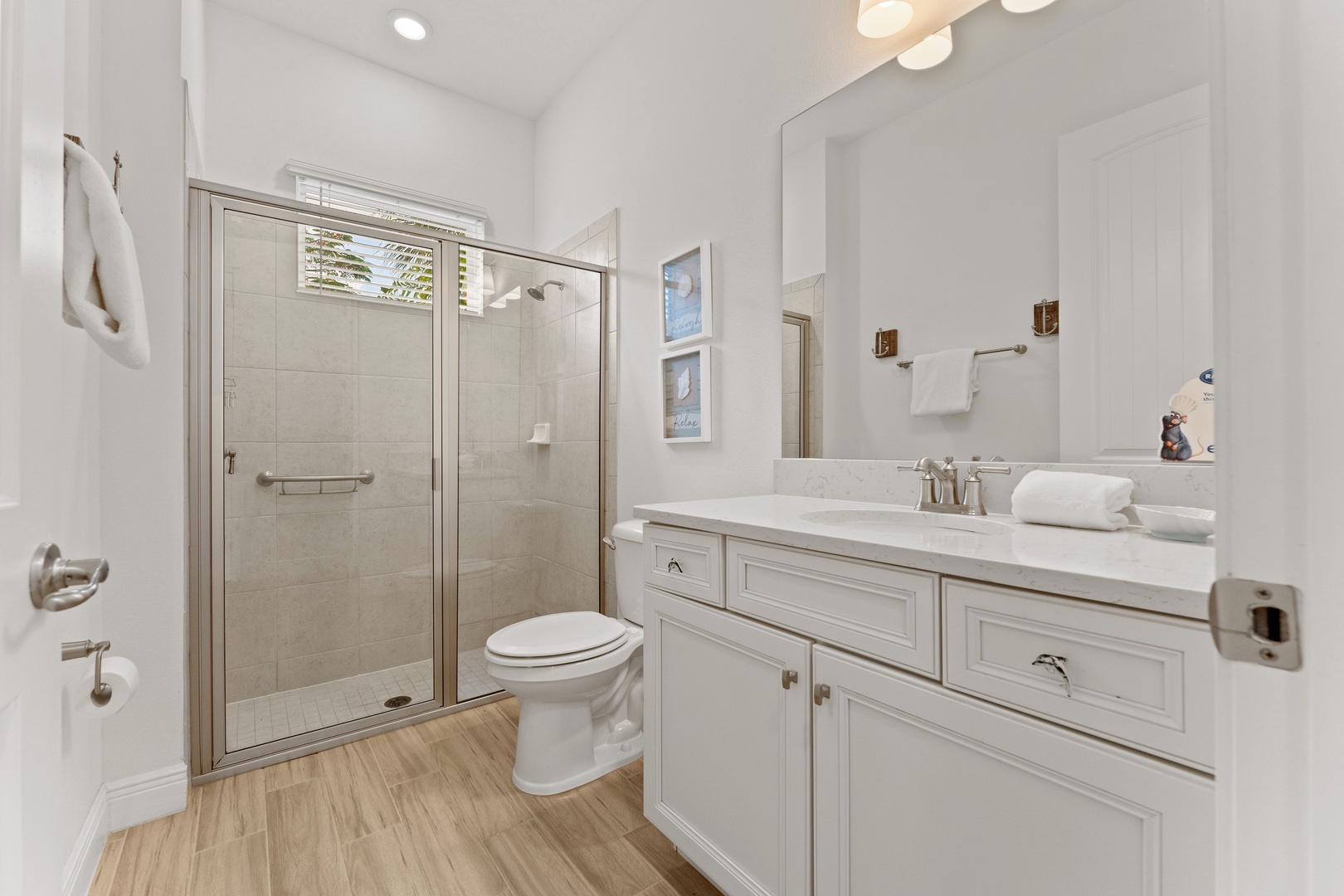 A chic single vanity & glass shower await in this main-level ensuite