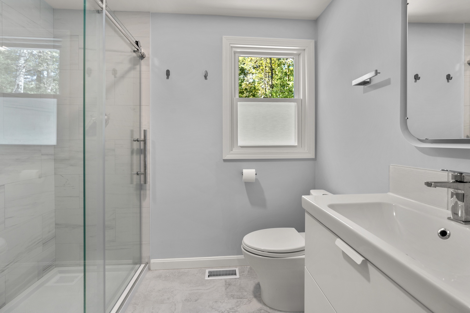 This main-floor full bath includes a single vanity, glass shower, & laundry