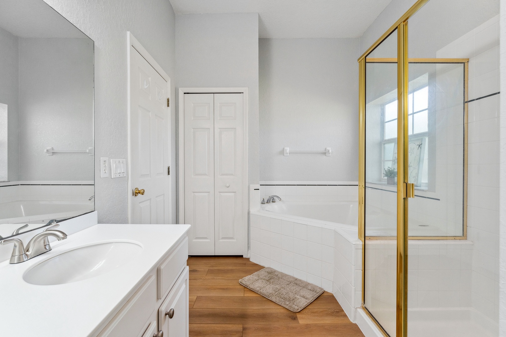 This ensuite bath features a single vanity, glass shower, and soaking tub