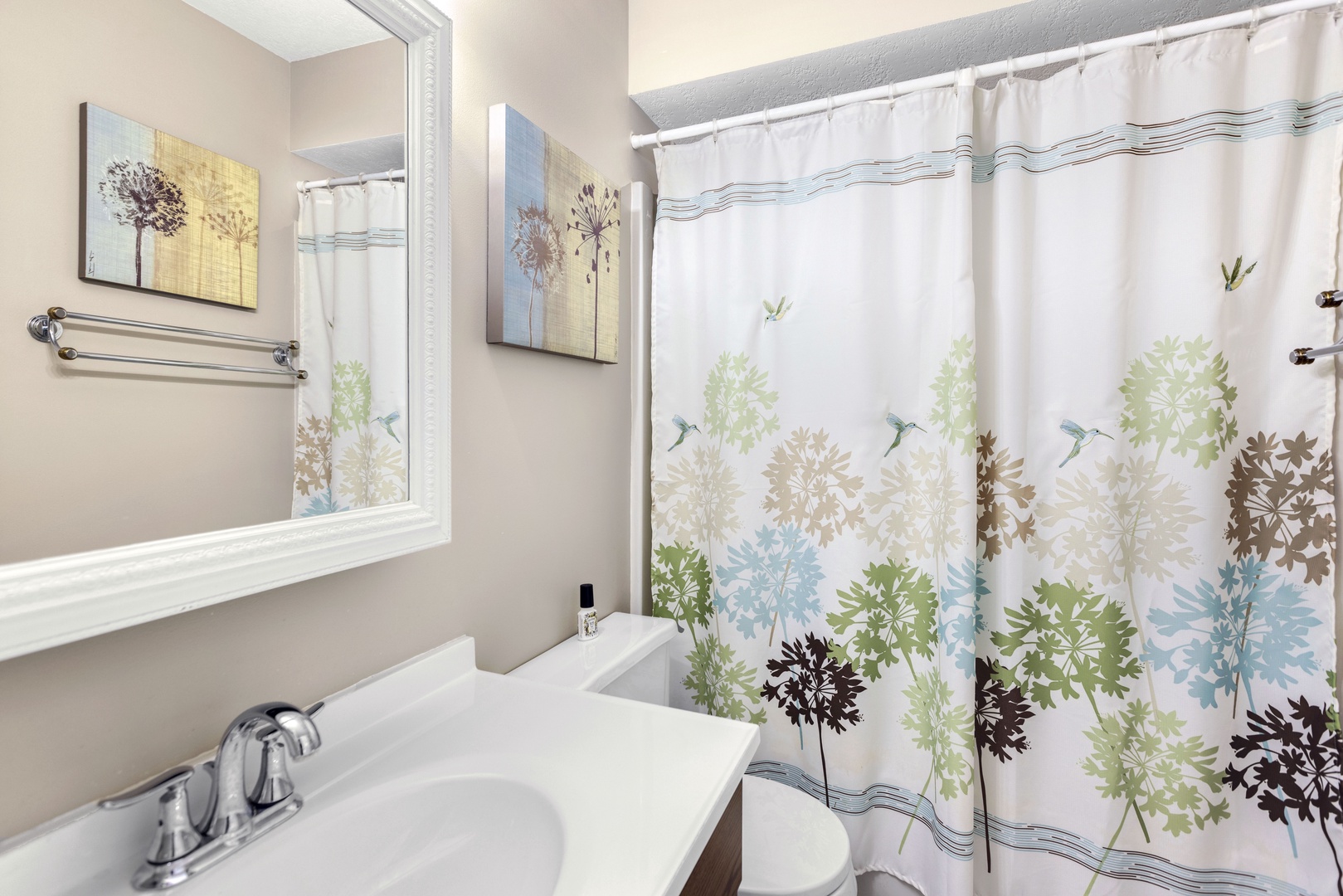 This shared bathroom contains a single vanity & shower/tub combo