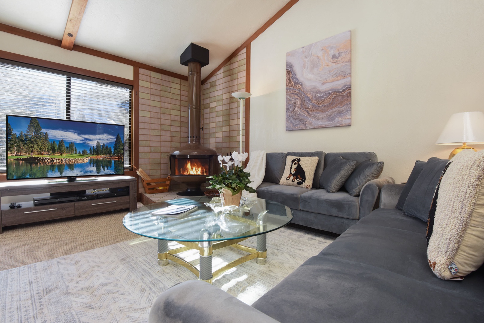 Living room with flat screen TV, wood burning fireplace, balcony access and high ceilings