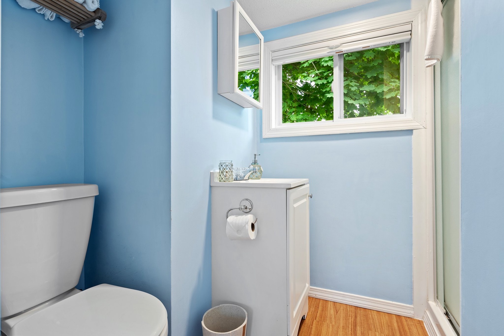 The airy full bath features a single vanity & glass shower