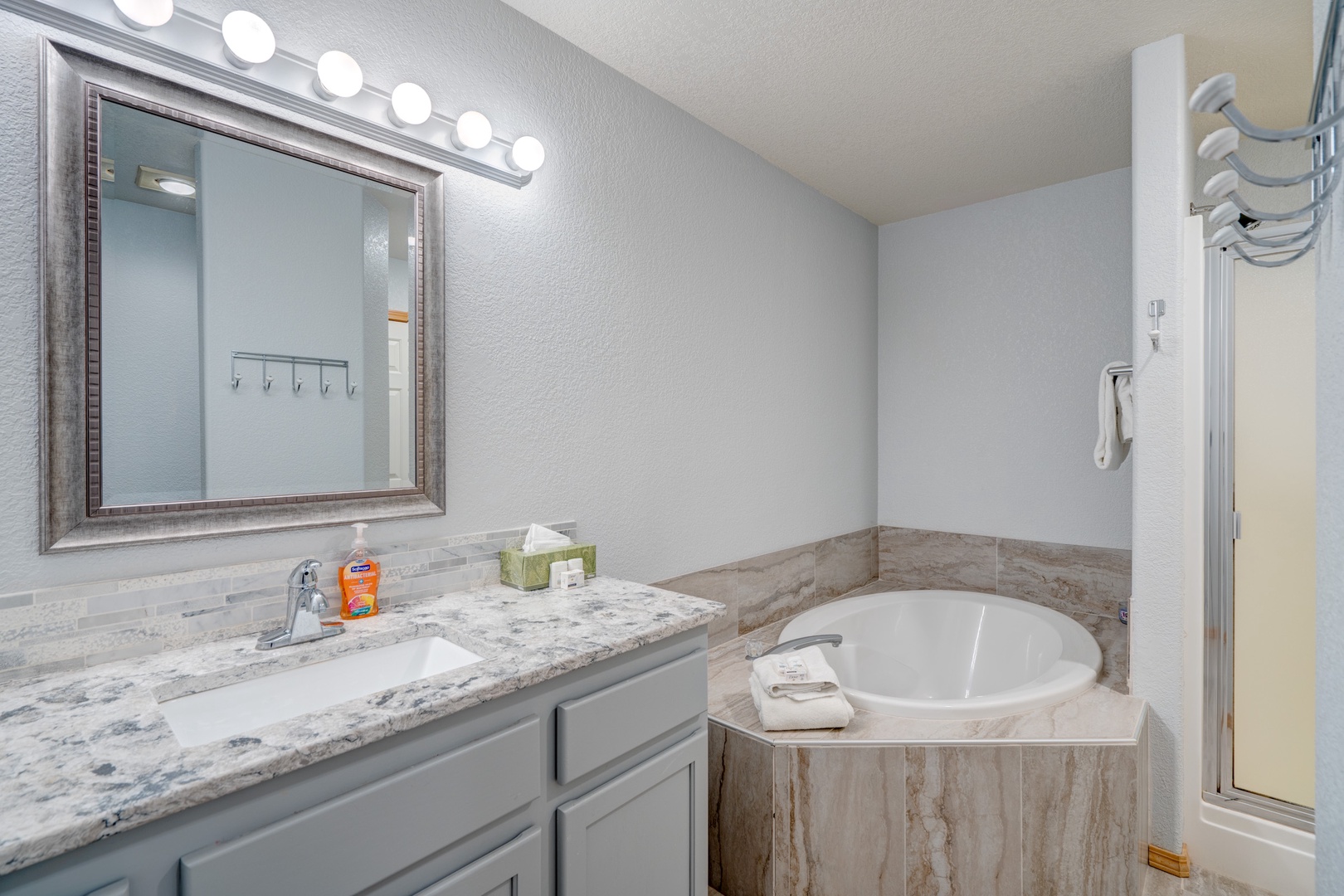 The final ensuite bath showcases a single vanity, shower, & luxe soaking tub