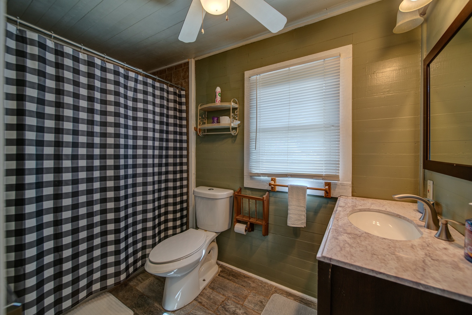 This charming full bathroom includes a single vanity & shower/tub combo