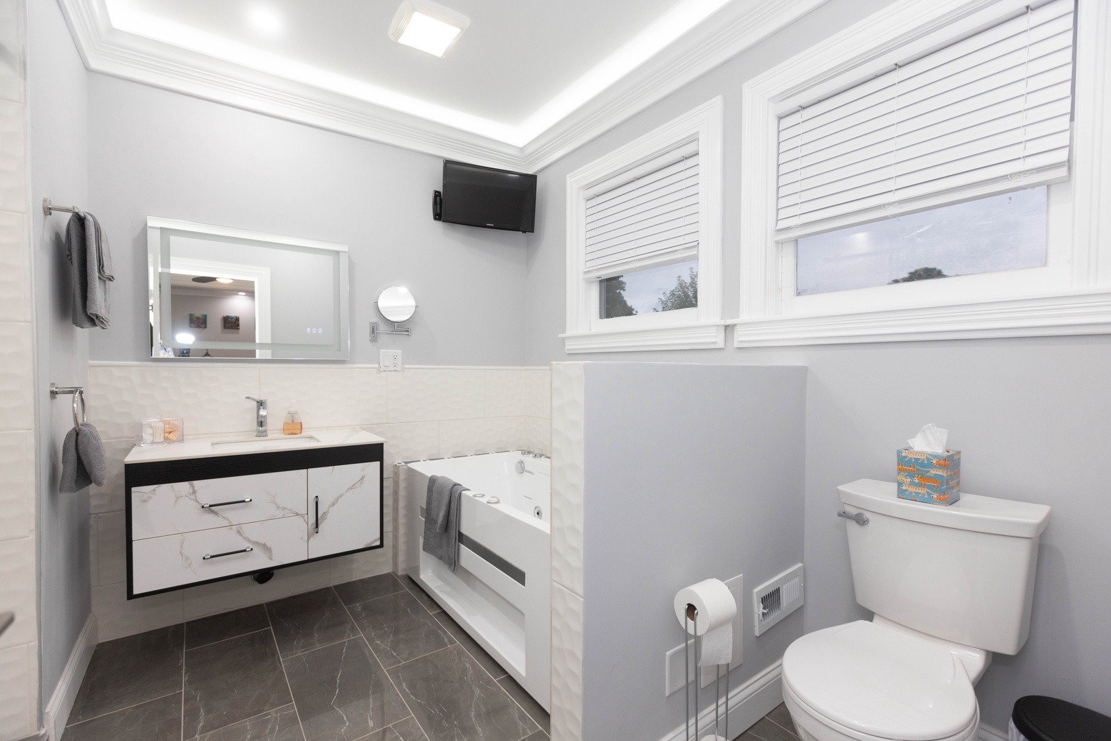 This en suite bath offers a single vanity, shower, & Jacuzzi tub