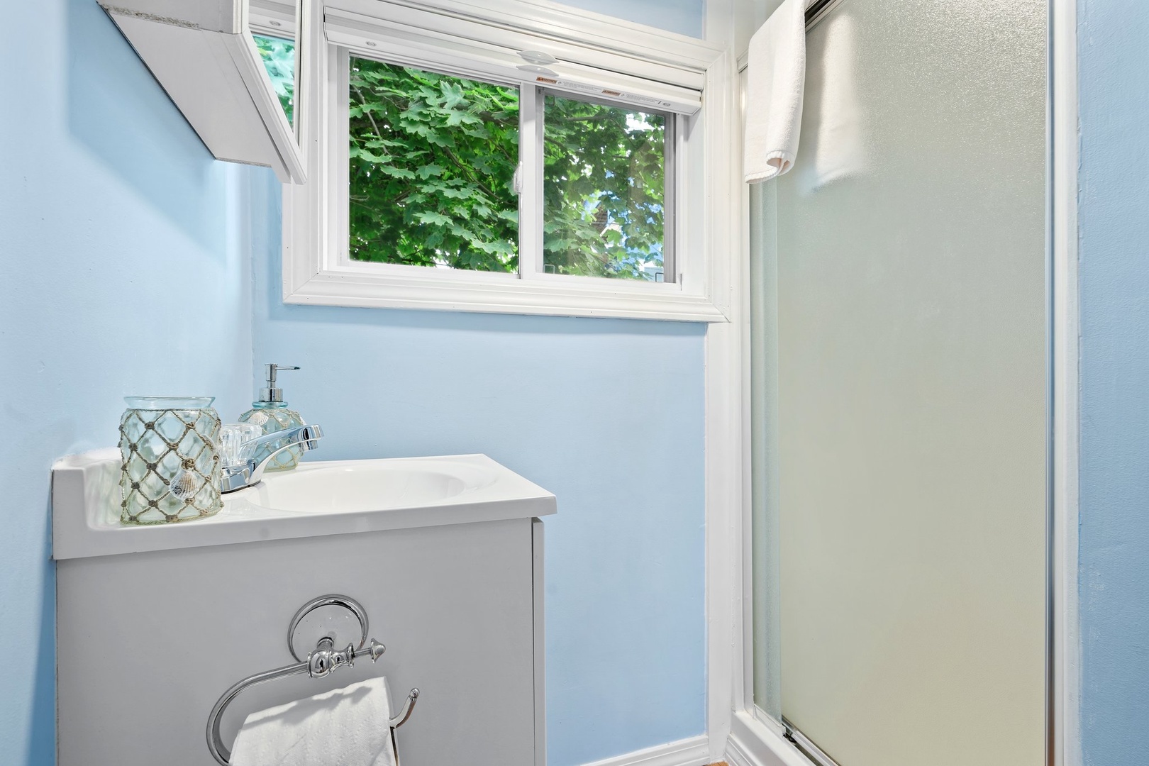 The tranquil full bath features a single vanity & glass shower