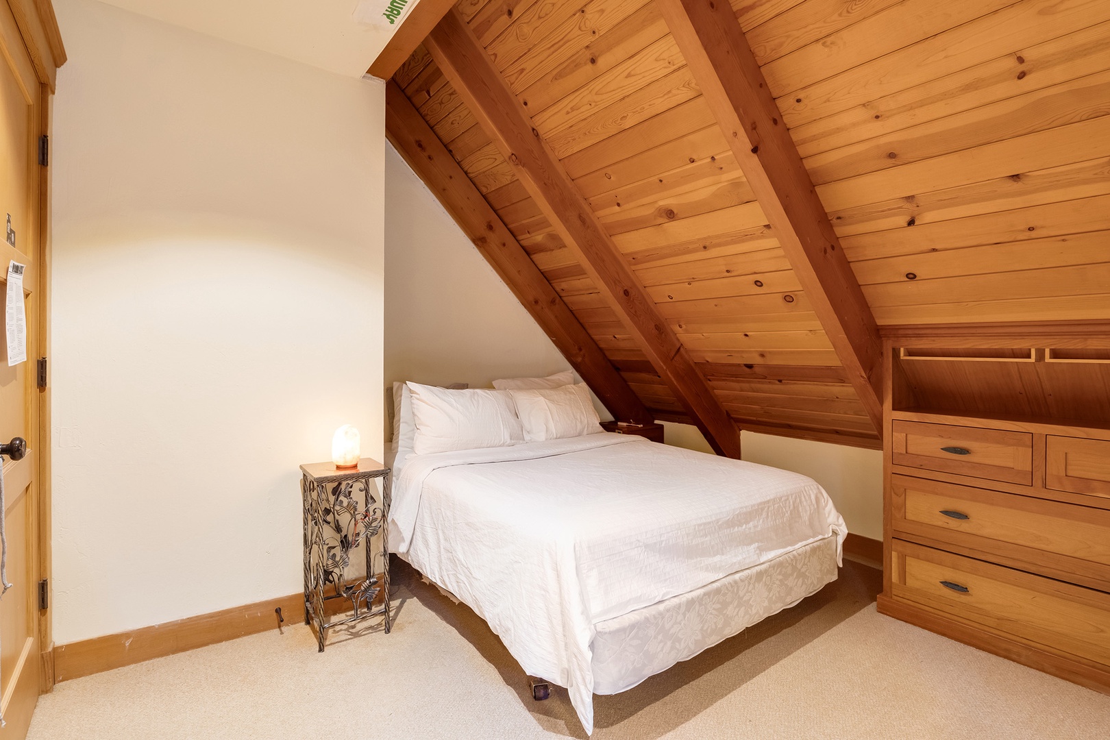 The cozy third-floor queen bedroom features a workspace with forest views