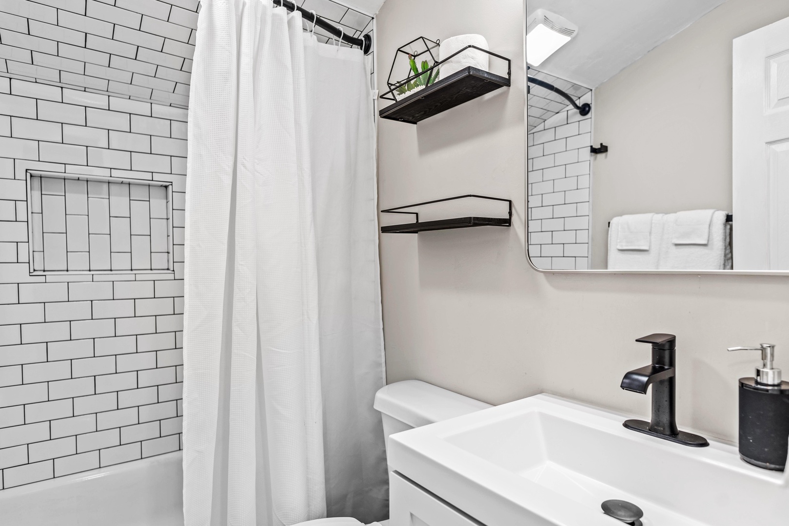 The full bathroom boasts chic finishes & a shower/tub combo