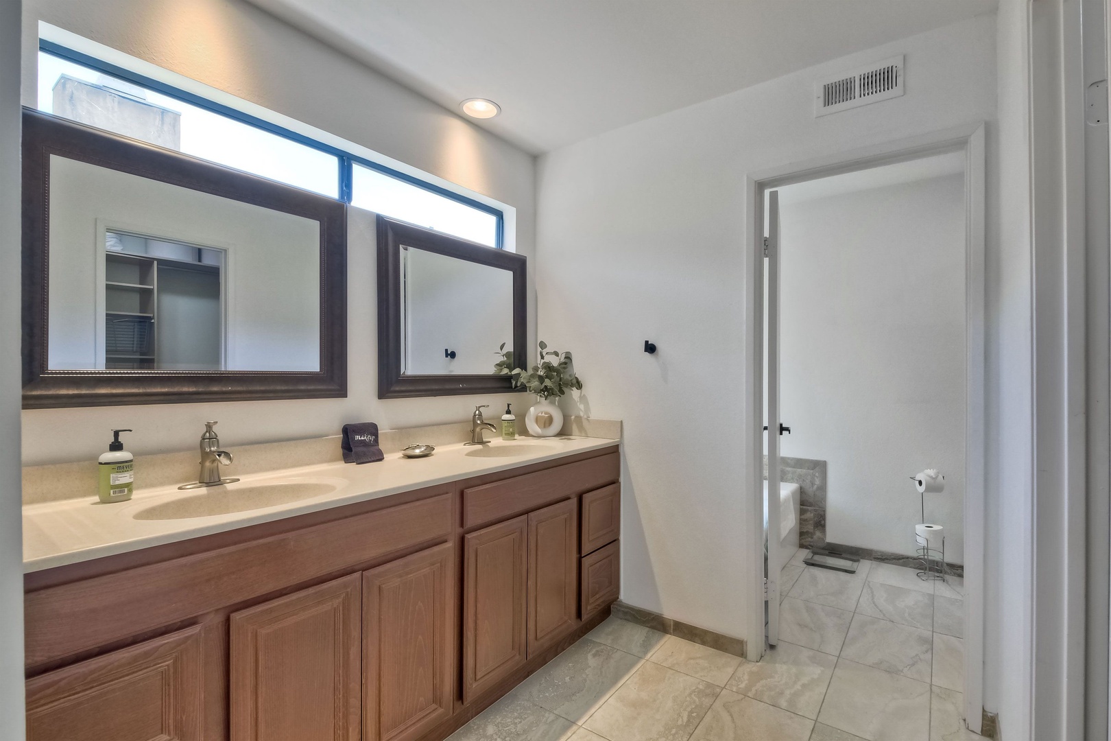 Ensuite bathroom with dual sinks, soaking tub, and stand-up shower