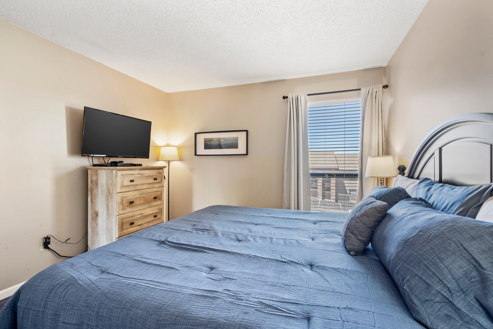 The tranquil primary suite boasts a plush king bed, ensuite, & TV