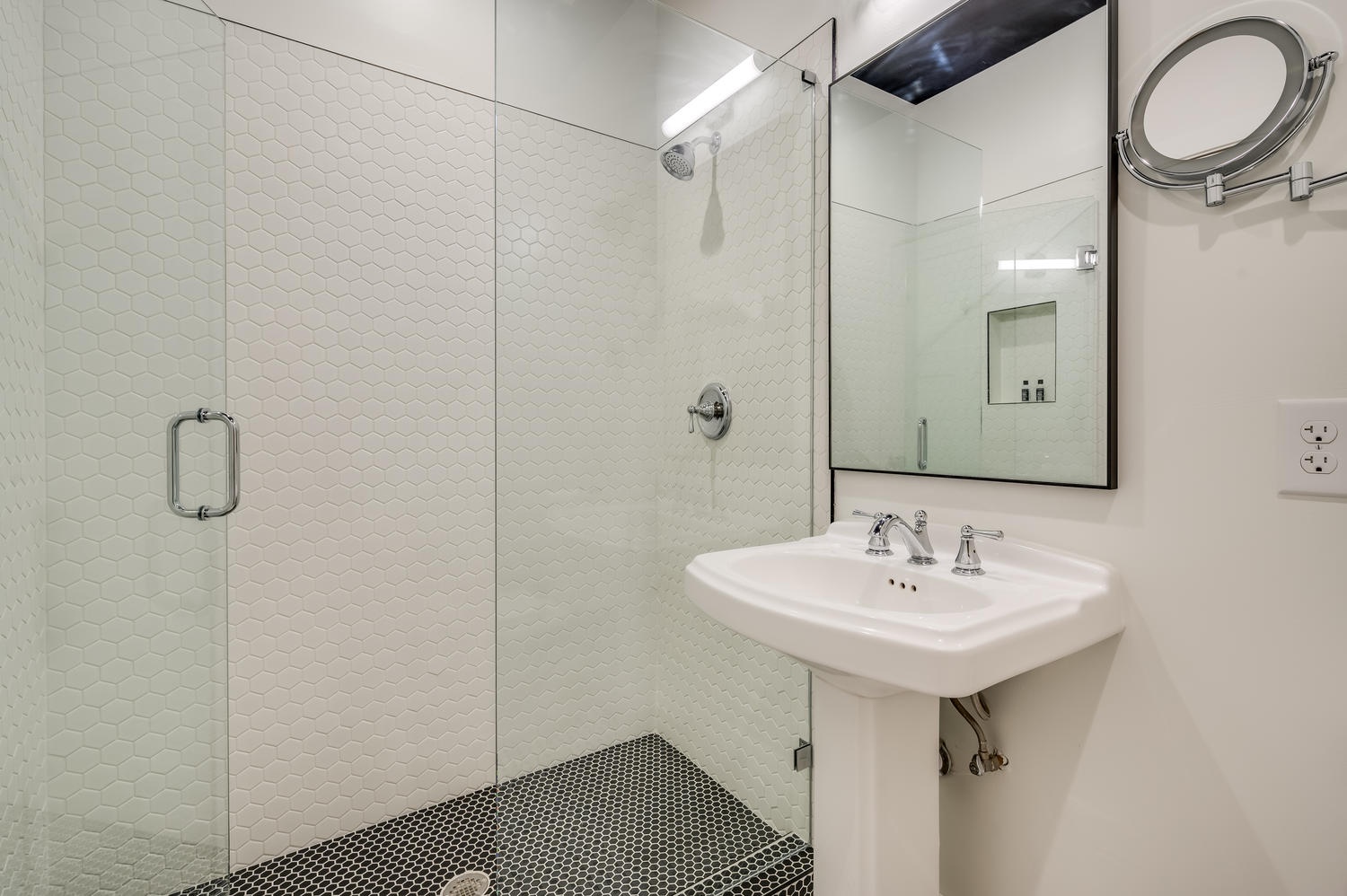 Suite 201 – The 2nd Floor Red, White & Black En Suite offers a pedestal sink with makeup mirror and luxurious Glass-Enclosed Shower