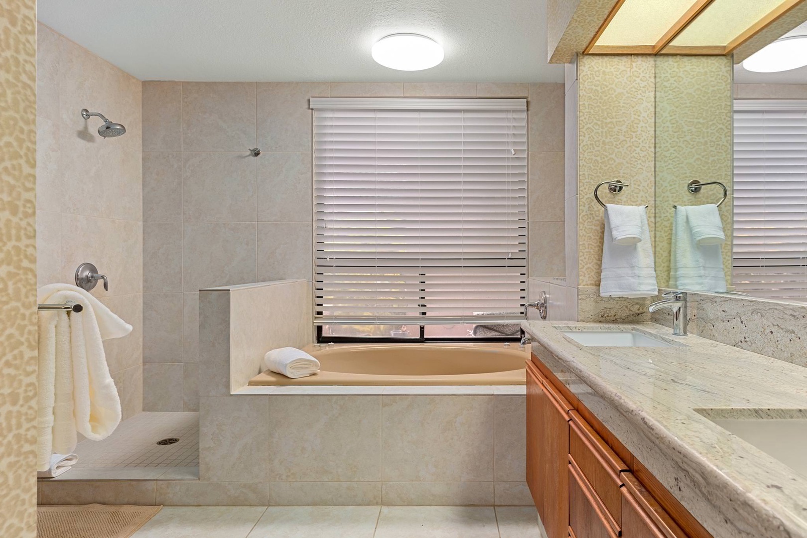 En suite bathroom with soaking tub, standing shower, and dual sinks