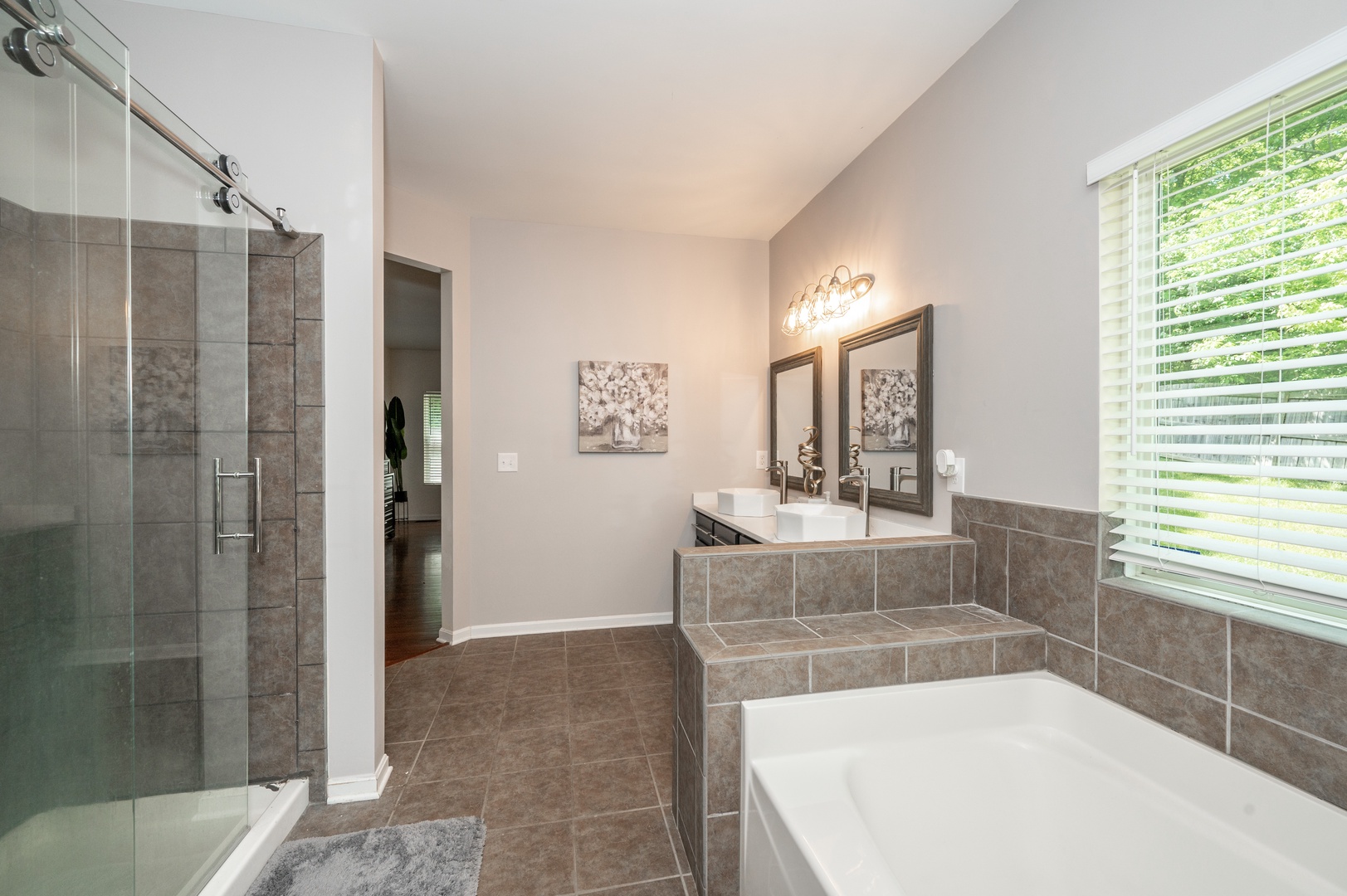 The 1st floor king en suite offers a chic double vanity, shower, & soaking tub