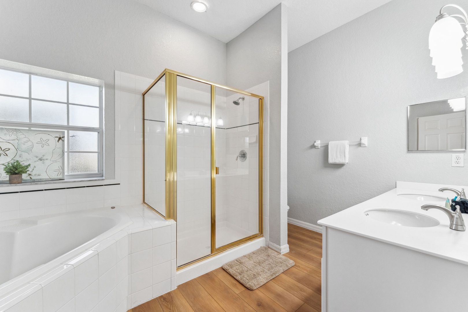 This ensuite bath features a single vanity, glass shower, and soaking tub