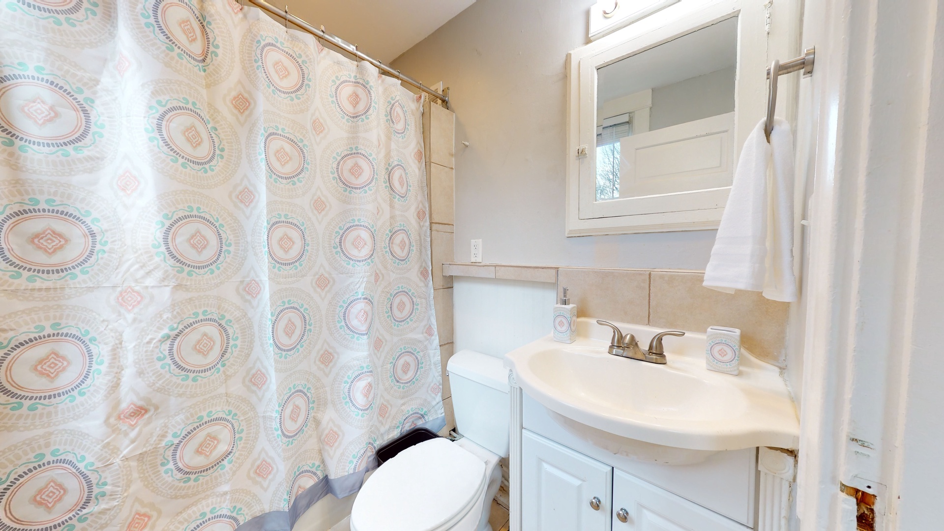 The full bath features a single vanity, mirror storage, & shower/tub combo