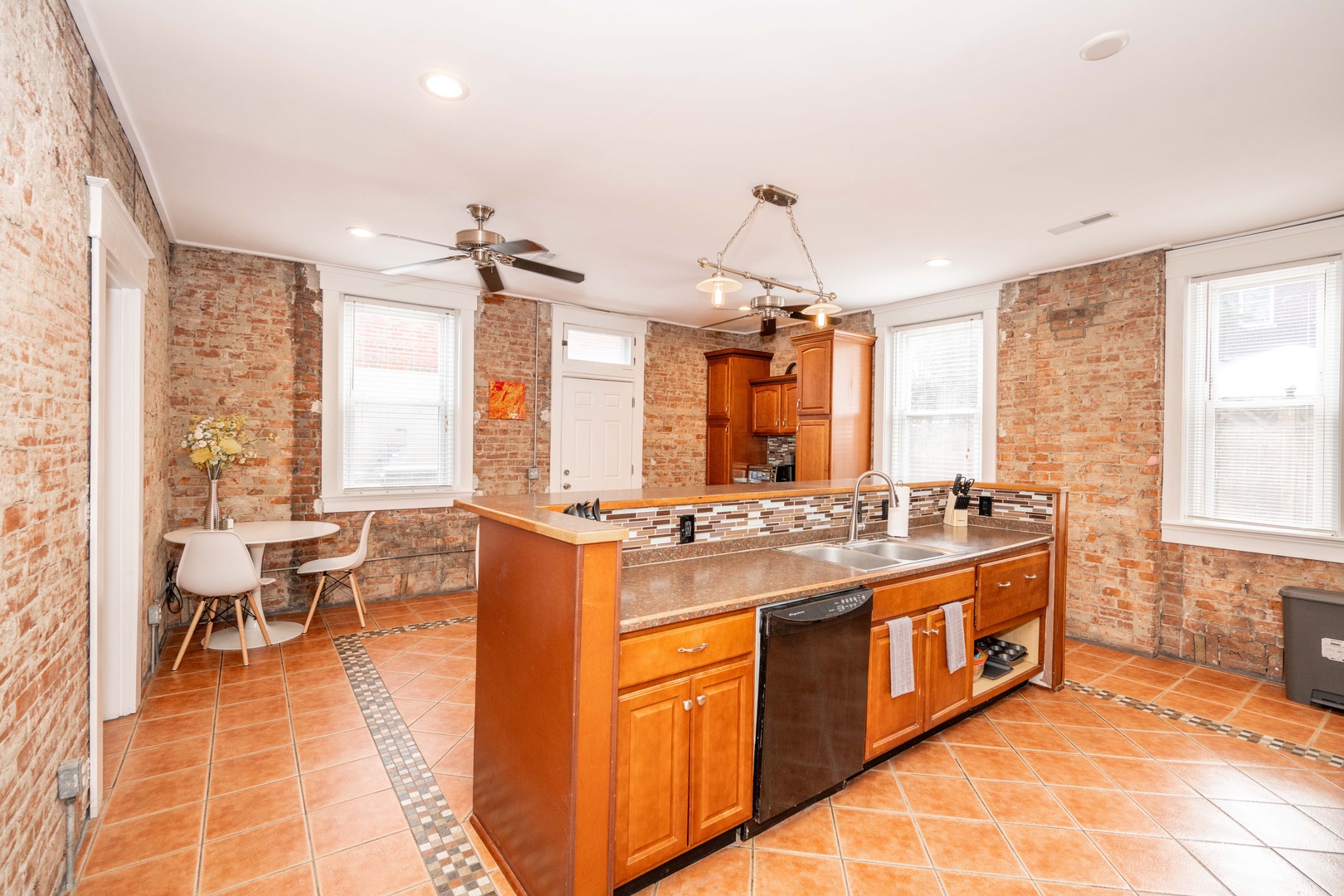 The kitchen showcases exposed brick, ample space, & numerous amenities