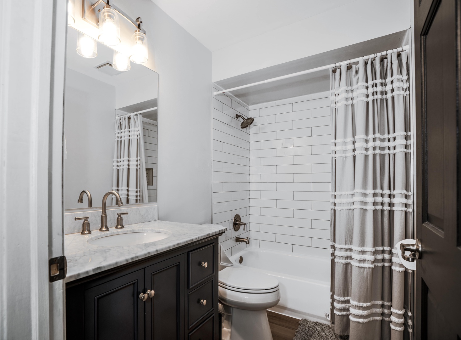 The full bath features a sleek single vanity & shower/tub combo