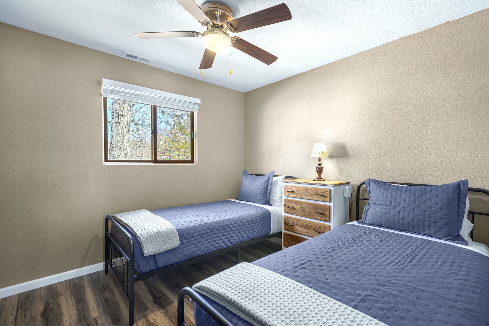 This cozy bedroom offers a pair of twin beds & ceiling fan