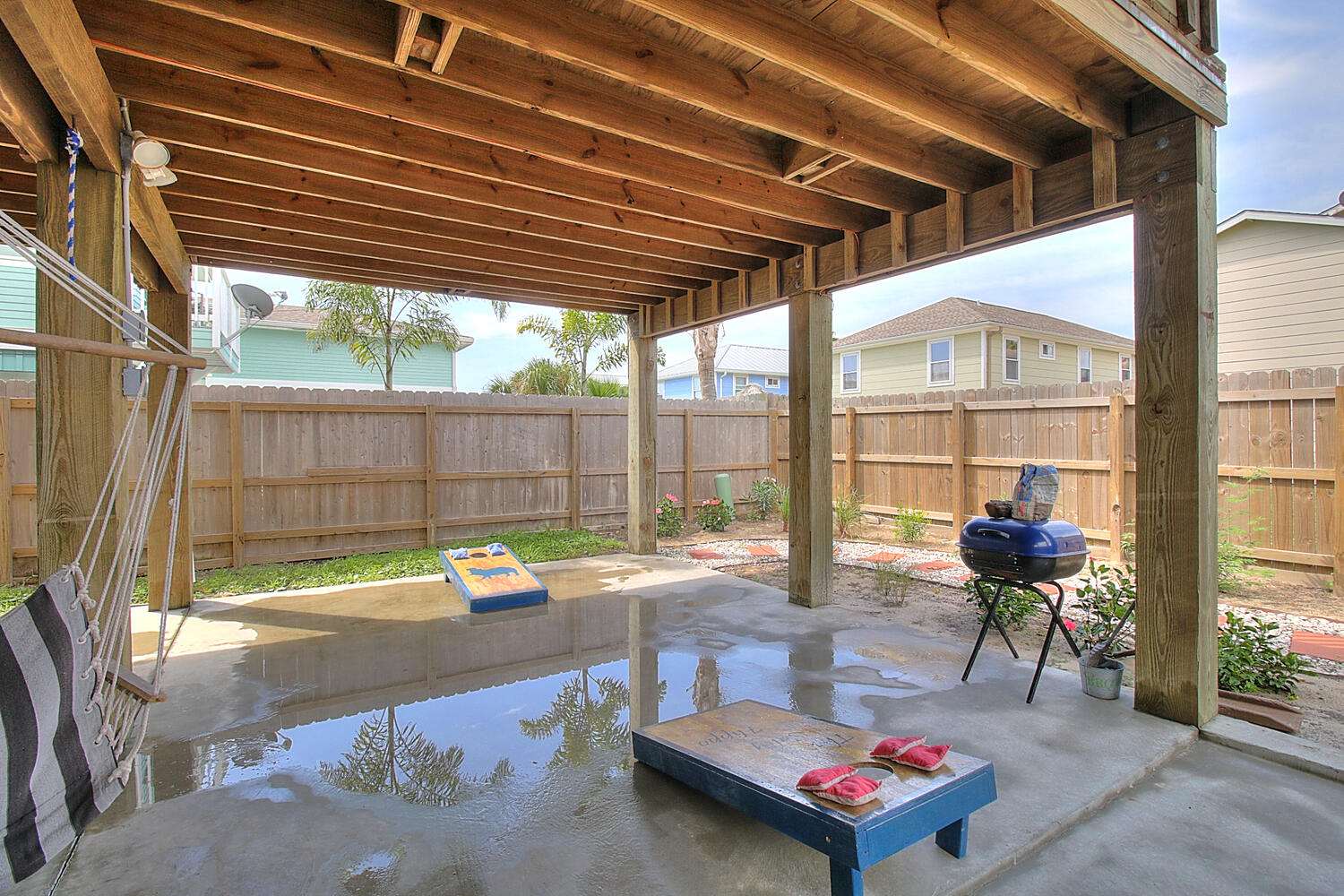 Back yard with outdoor seating, grill, and corn hole game