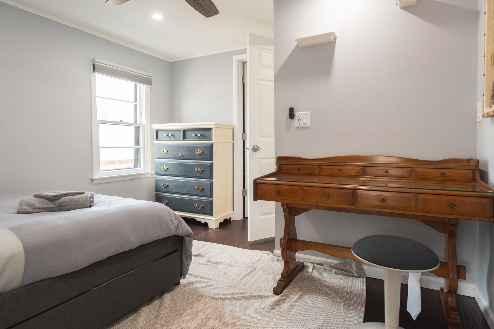 The apartment’s bedroom offers a full-sized bed, desk, & ceiling fan