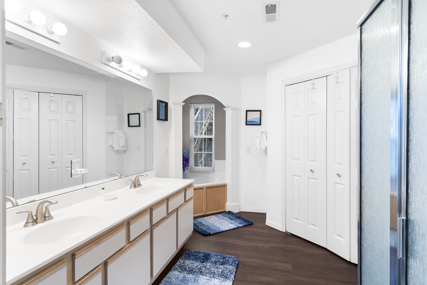 This luxe ensuite features a double vanity, glass shower, & soaking tub