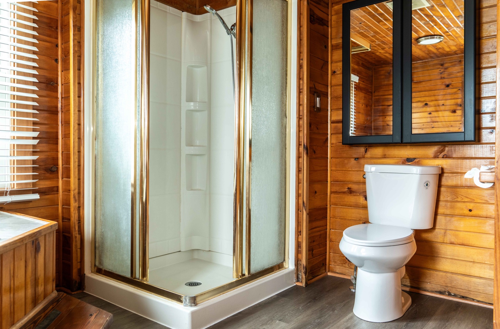 The full bath features a single vanity, glass shower, & luxe soaking tub