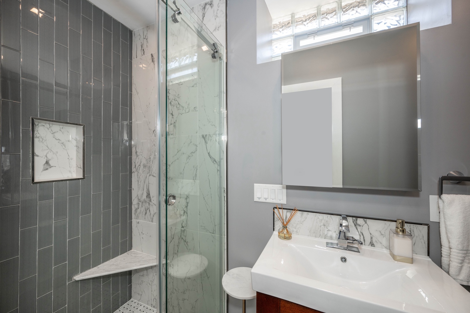 The chic full bath features a single vanity & glass shower