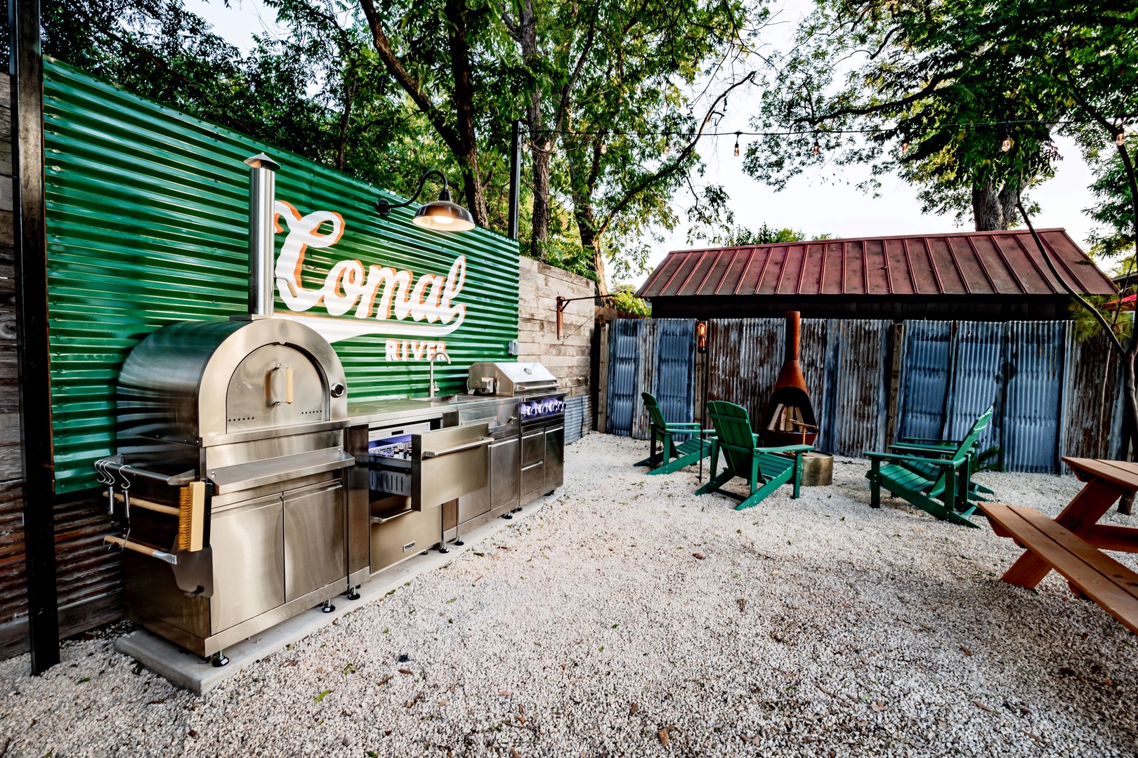 The back yard picnic area boasts a firepit, grill, pizza oven, & outdoor fridge