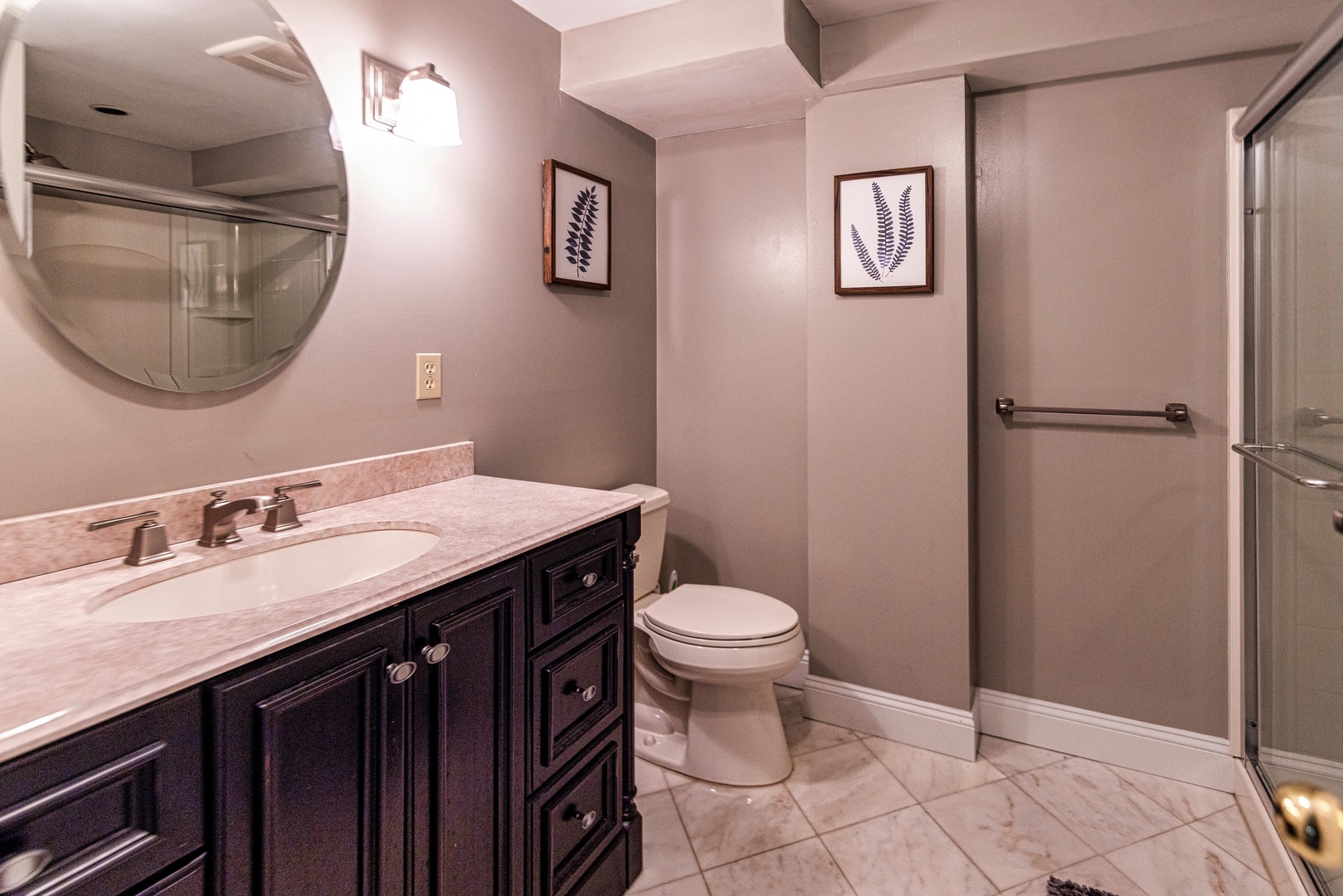 This lower-level full bath includes a large single vanity & glass shower