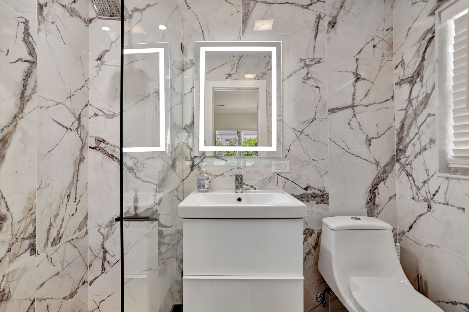 This queen ensuite features a sleek single vanity & glass shower