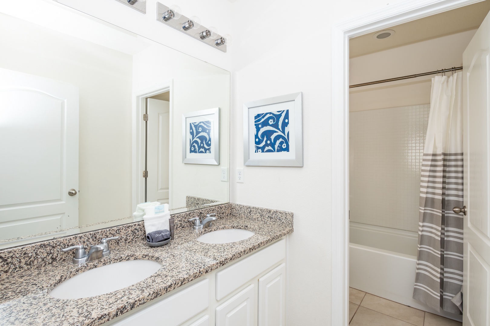 Shared bathroom with double vanity and shower/tub combo