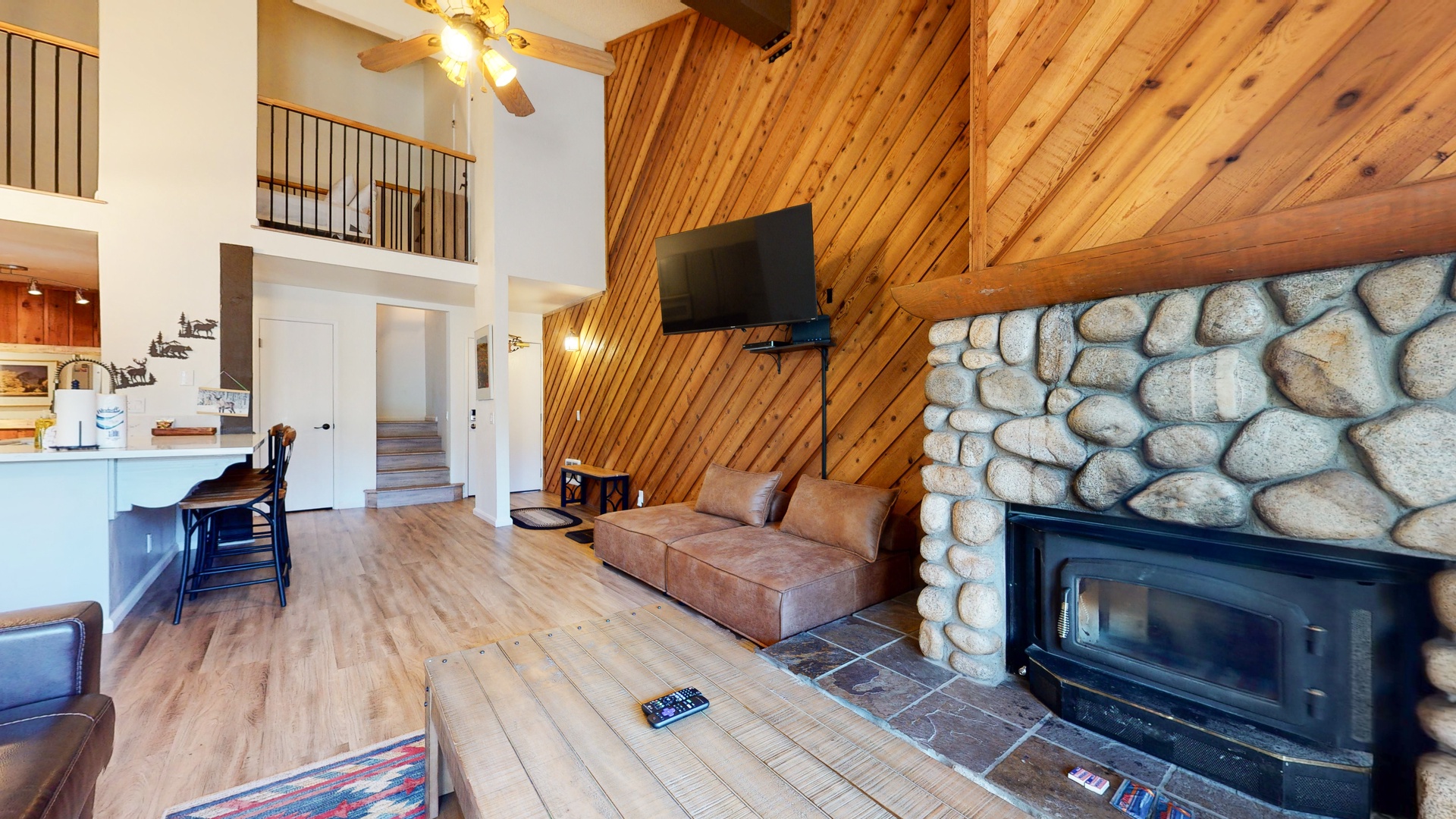 Open living space with sofa, sleeper, TV, fireplace, and balcony