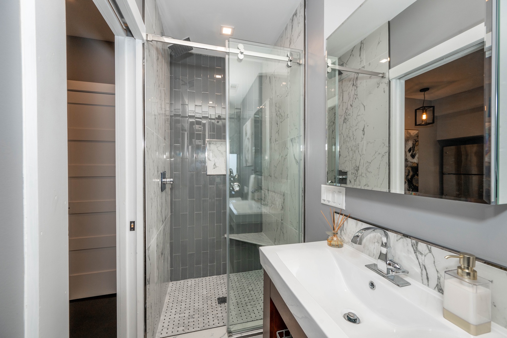 The chic full bath features a single vanity & glass shower