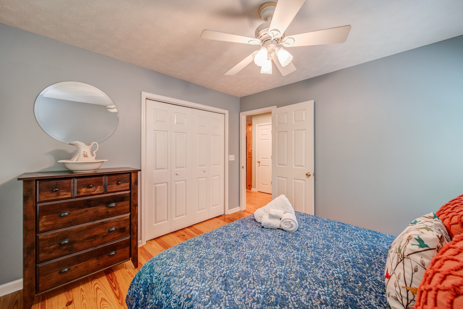The first of two queen bedrooms, with a dresser & ceiling fan