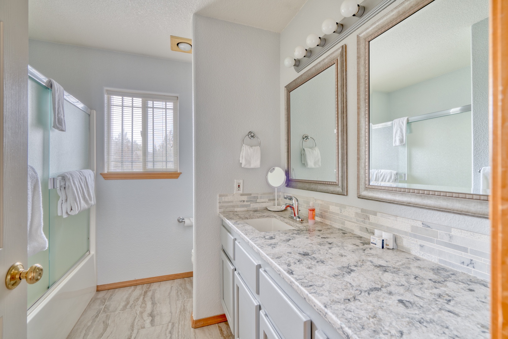 This hall bathroom features a large single vanity & shower/tub combo