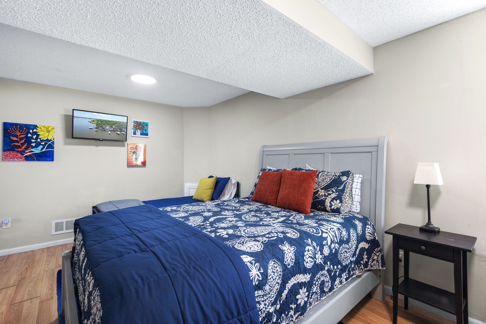 The lower-level bedroom offers a queen bed, a pair of twin beds, & Smart TV