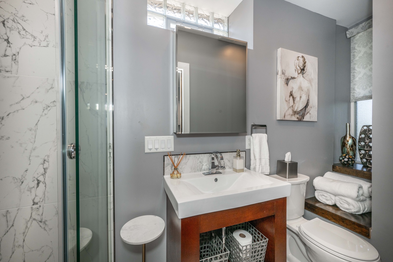 The chic full bath features a single vanity & glass shower