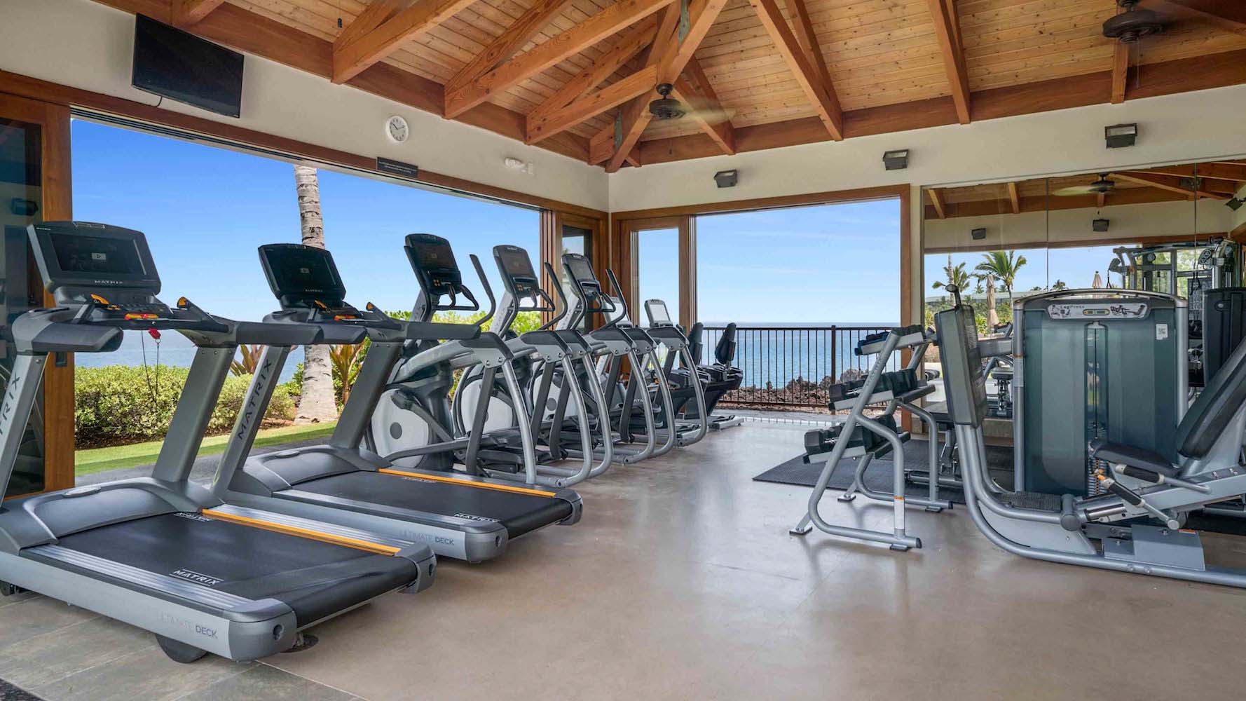 Modern gym with large windows, ocean view, and high wood ceiling