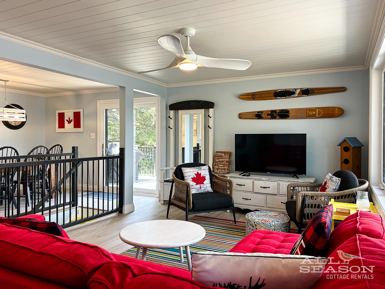 Cozy up in this charming Canadian cottage living room with vintage water skis, plush red seating, and rustic touches that make you feel right at home.