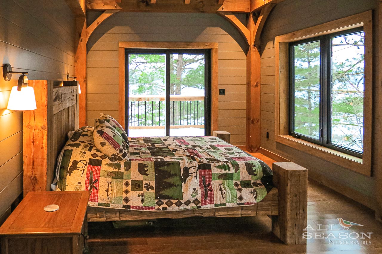 Drift off in your cozy rustic bedroom with handcrafted wooden beams and charming quilt bedding overlooking peaceful wooded grounds.