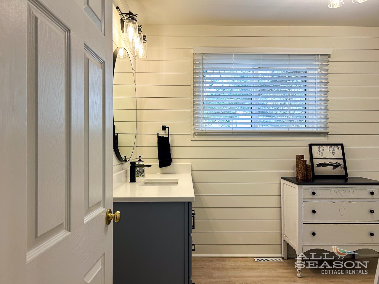 Refresh in your stylish bathroom with sleek fixtures, shiplap walls, and natural light streaming through the window blinds.