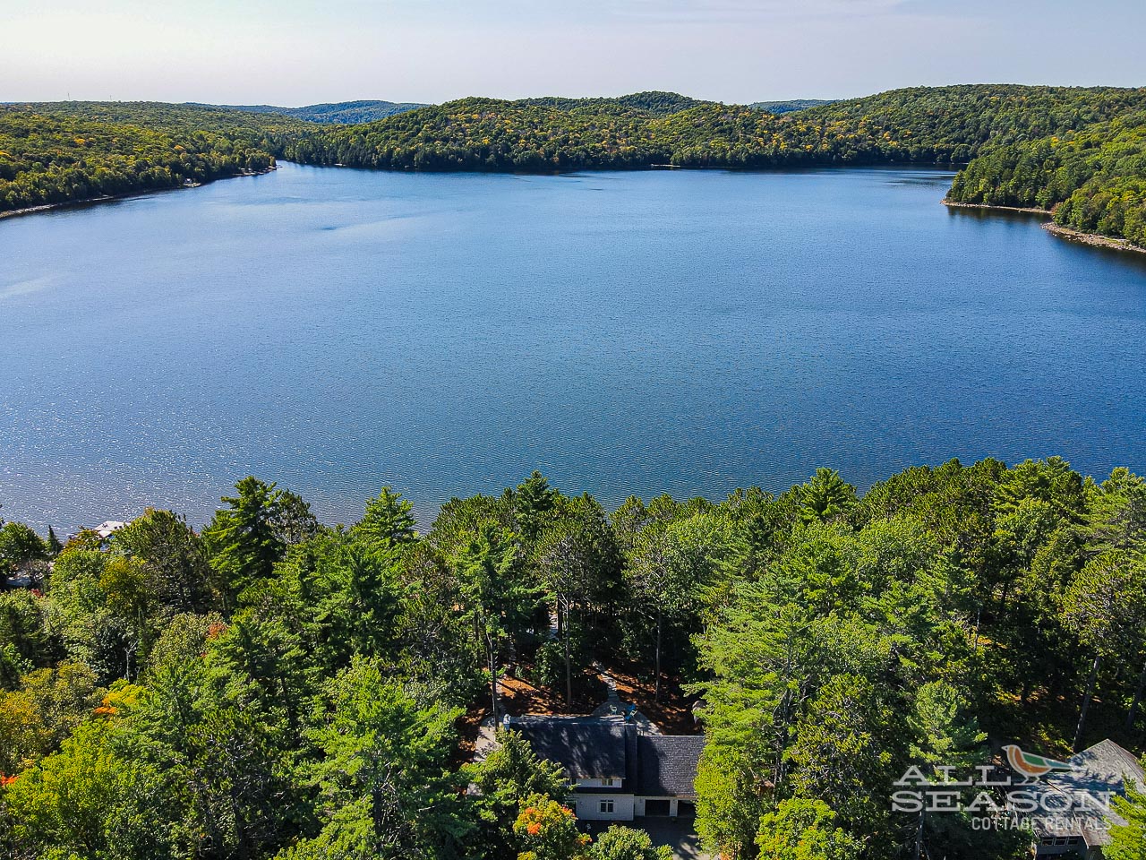 Aerial view showcasing the pristine lake and lush forested landscape surrounding the property area.