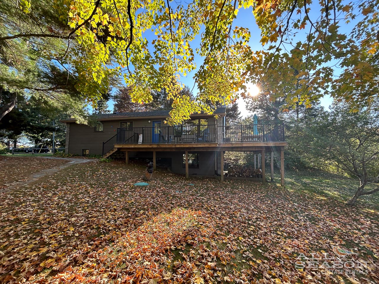 A charming retreat nestled among vibrant autumn trees, featuring a welcoming elevated deck perfect for morning coffee and peaceful moments surrounded by nature's seasonal beauty.