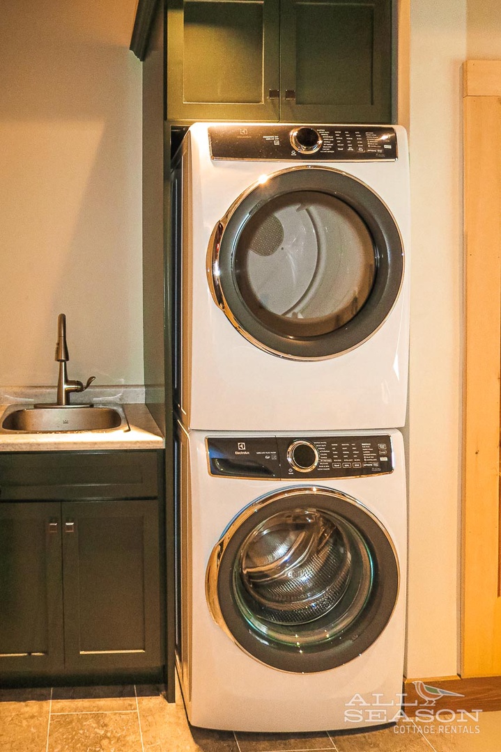Your own in-unit washer and dryer make extended stays effortless, tucked neatly into dark cabinetry beside a convenient utility sink.